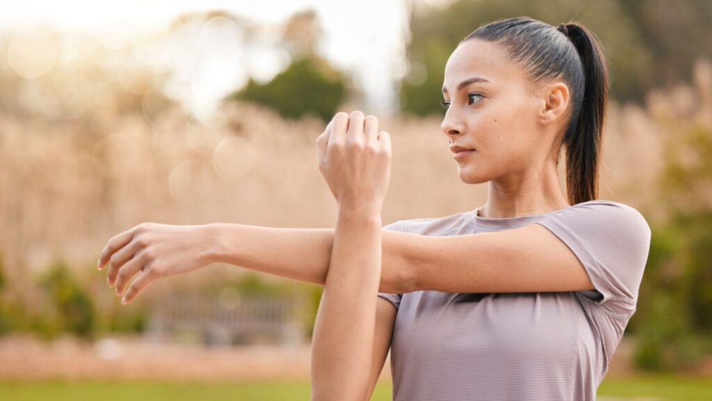 Health, fitness and woman stretching arms in nature to get ready for workout, training or exercise. Sports, thinking and female athlete stretch and warm up