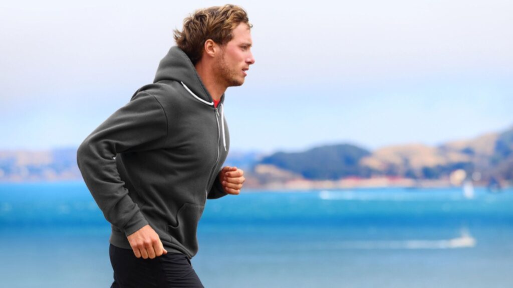 Man running in hoodie near water