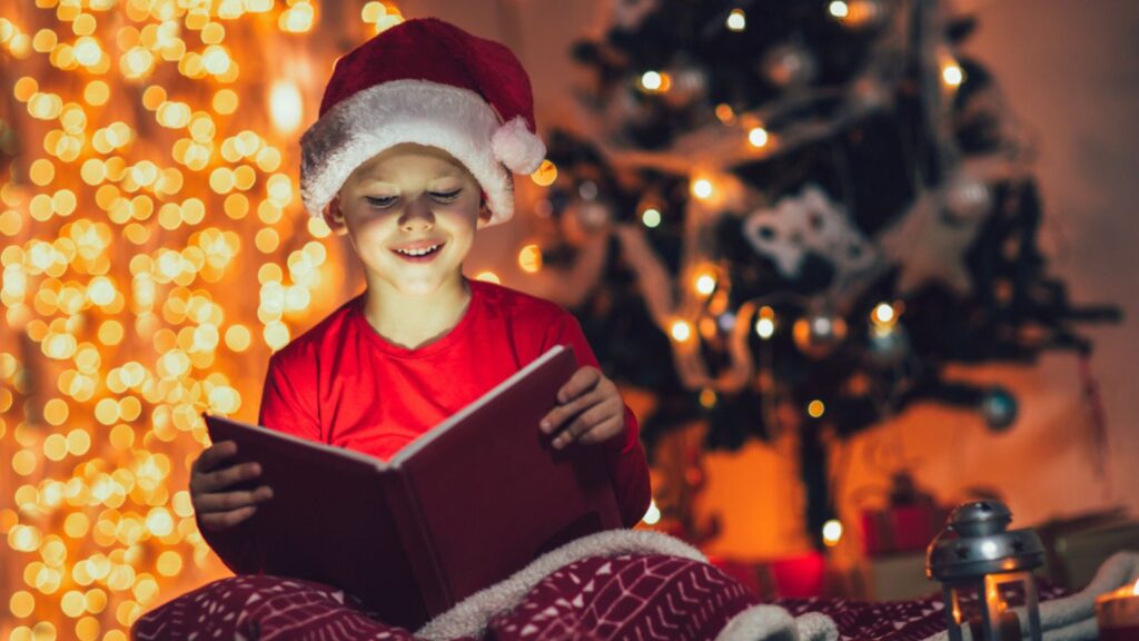 Surprised child opening magic Christmas book. Xmas holiday concept