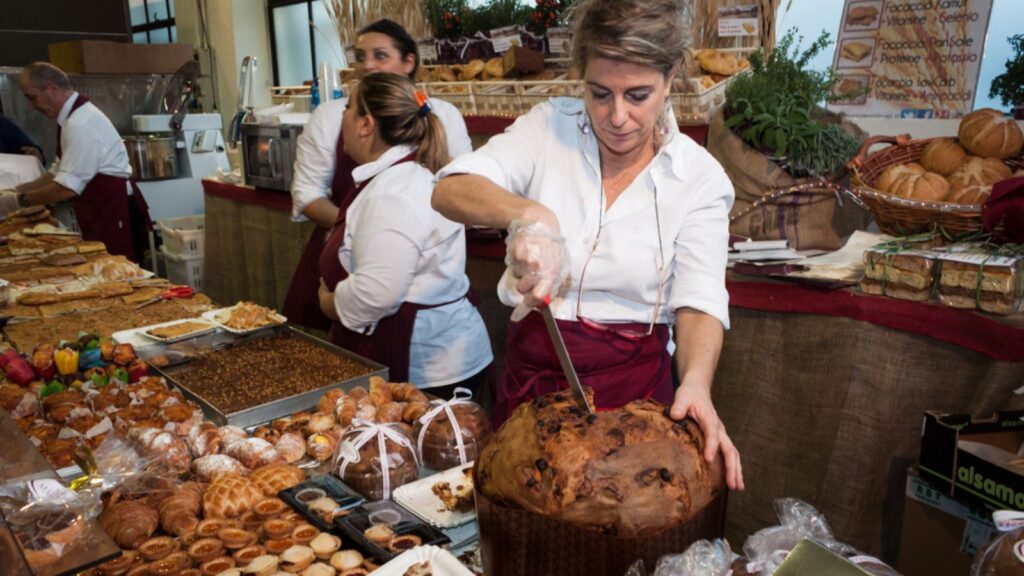 woman cuts a slice of panettone, traditional Christmas cake from Milan, at Golosaria, important event dedicated to culture and tradition of quality food and wine on NOVEMBER 16, 2013 in Milan